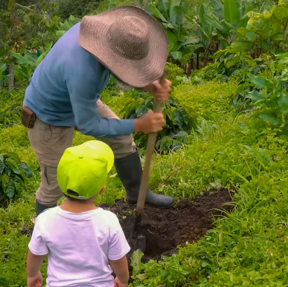 Un agricultor toma una muestra de suelo bajo la mirada de un niño